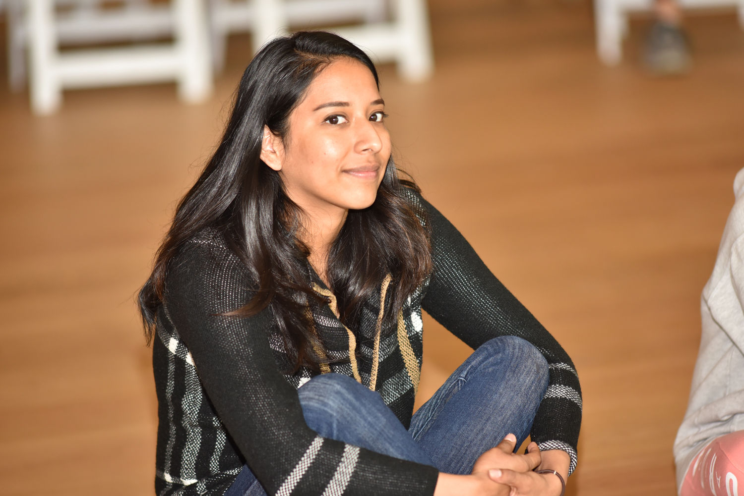 Russel Altamirano smiles at the camera, siting cross-legged and on the hardwood floor at the Hammer Museum