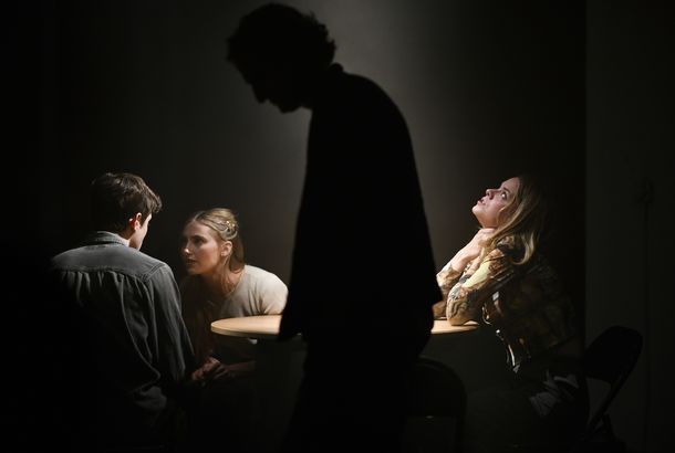 Three people at a table with the silhouette of a figure in front