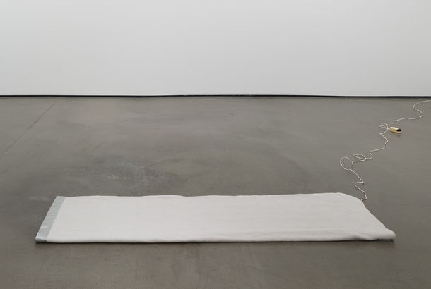 A gray electric blanket on an otherwise empty gallery floor