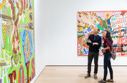 Two people look up at a large painting in a gallery