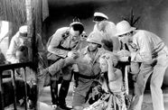 Still from the film Safe in Hell (1931) showing a woman on the ground with a group of soldiers
