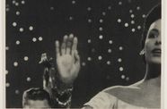 Half of a woman's face, with her hand lifted, on a background of stars