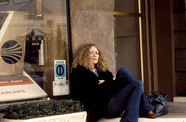 Still from the film Dusty and Sweets McGee (1971) showing a woman seated on the sidewalk, leaning against a building