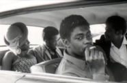 Still from the film Several Friends (1969) showing four people in a car with the man in the foreground smoking a cigarette