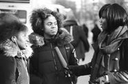 Two teenage girls stand before a woman with a microphone
