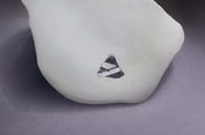 A white stone with a small black-and-white cutout on a grey background