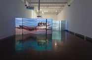 A dark gallery with two projector screens