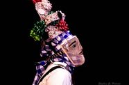 A masked dancer with tall headdress viewed in profile