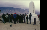 Still from the film Pilgrimage showing a group gathered around a monument built at a former WWII concentration camp for Japanese Americans