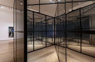 Looking inside a large, mirror-like cube with intersecting walls inside