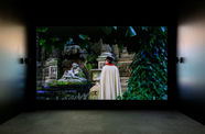 A screening room with an image of a caped man standing in a garden