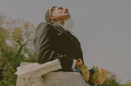 A man with a construction mask around his chin stands in a concrete tube, looking up at the sky