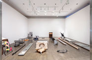 View of a room with white walls and a dark floor, with various objects sitting on the floor. 