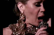 A woman in sparkly jewelry sings into a microphone