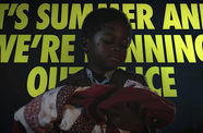 Still from the HBO television series "Watchmen," showing a young black boy holding a baby wrapped in a blanket, superimposed over large yellow type that reads "IT'S SUMMER AND WE ARE RUNNING OUT OF ICE"