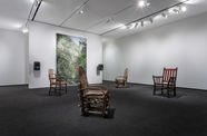 Four wooden chairs sit in the same room as David Hartt's painting