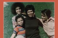 Mother with three children smiling on grass field.