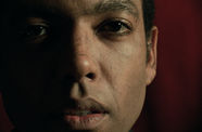 Closeup of man's face in dim lighting. Half of his face is in the shadows.