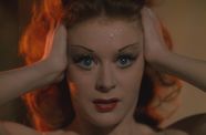 Closeup of woman wearing thin, angular strokes of eyeliner holding her head