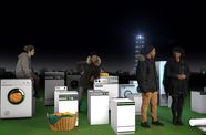Four people stand among several washing machines in front of a night skyline