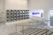 Four rows of silver air conditioners stand stacked on top of each other in a museum lobby. 
