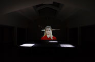 Portrait of person projected large on one wall in a big room