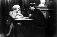 Still from the black and white film "The Docks of New York" (1928) showing a man and a woman talking at a table