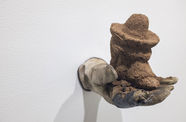 Sculpture of a gloved hand holding an object made of soil and birdseed.