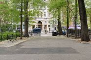 Photo taken from a park of of a blue van in front of a building in New York.