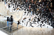 A family stares at pieces of wood and debris hung up ona. wall.