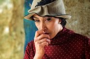A woman holds her face, pondering