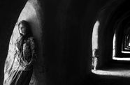 A man and a woman stand in dark corridors. 