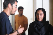 A man with glasses speaks to a woman in a hijab. 
