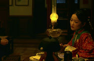 A man and a woman sit in a dimly lit room. 