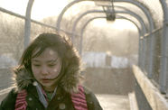 Woman in a puffy jacket walks through an archway. 