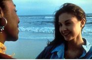 Two women speak to each other in front of the ocean.
