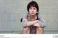 A woman sits on a sidewalk. 