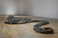 A mixed-media installation with steel chains and rope arranged on a gallery floor