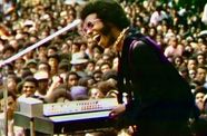 Still from the documentary film "Summer of Soul" (2021) showing Sly Stone performing in front of a large crowd