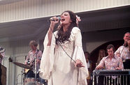 A woman in a white dress singing on stage in a still from the film "Nashville" (1975)