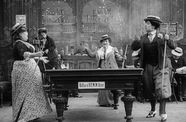 A group of women stand around a pool table. 