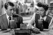 A man and woman make eye contact while sipping on milk shakes. 