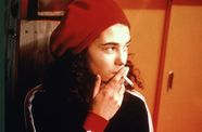 Woman wearing hat smokes cigarette. 
