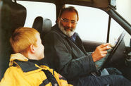 man driving looks over at child in passenger seat