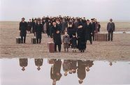 People stand on edge of water dressed formally