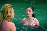 Two mermaids talk with their torsos above the surface of the water