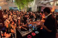 Photograph of a crowd of people dancing to a DJ in the foreground