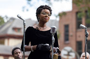 Still from the film "Till" (2022), depicting the character Mamie Till speaking in front of an array of microphones