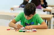 Child in a green shirt drawing with markers