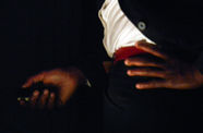 Close-up of a pair of hands, one holding something, one resting on a hip